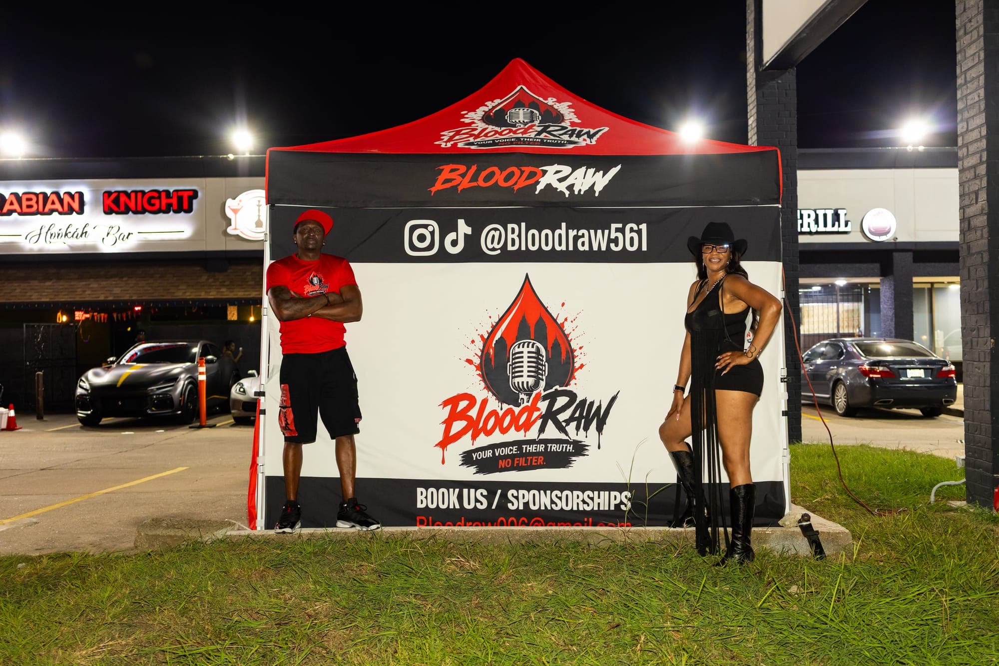 The BloodRaw sign board beside the tent, showing @Bloodraw561 and 'Book us / Sponsorships'.