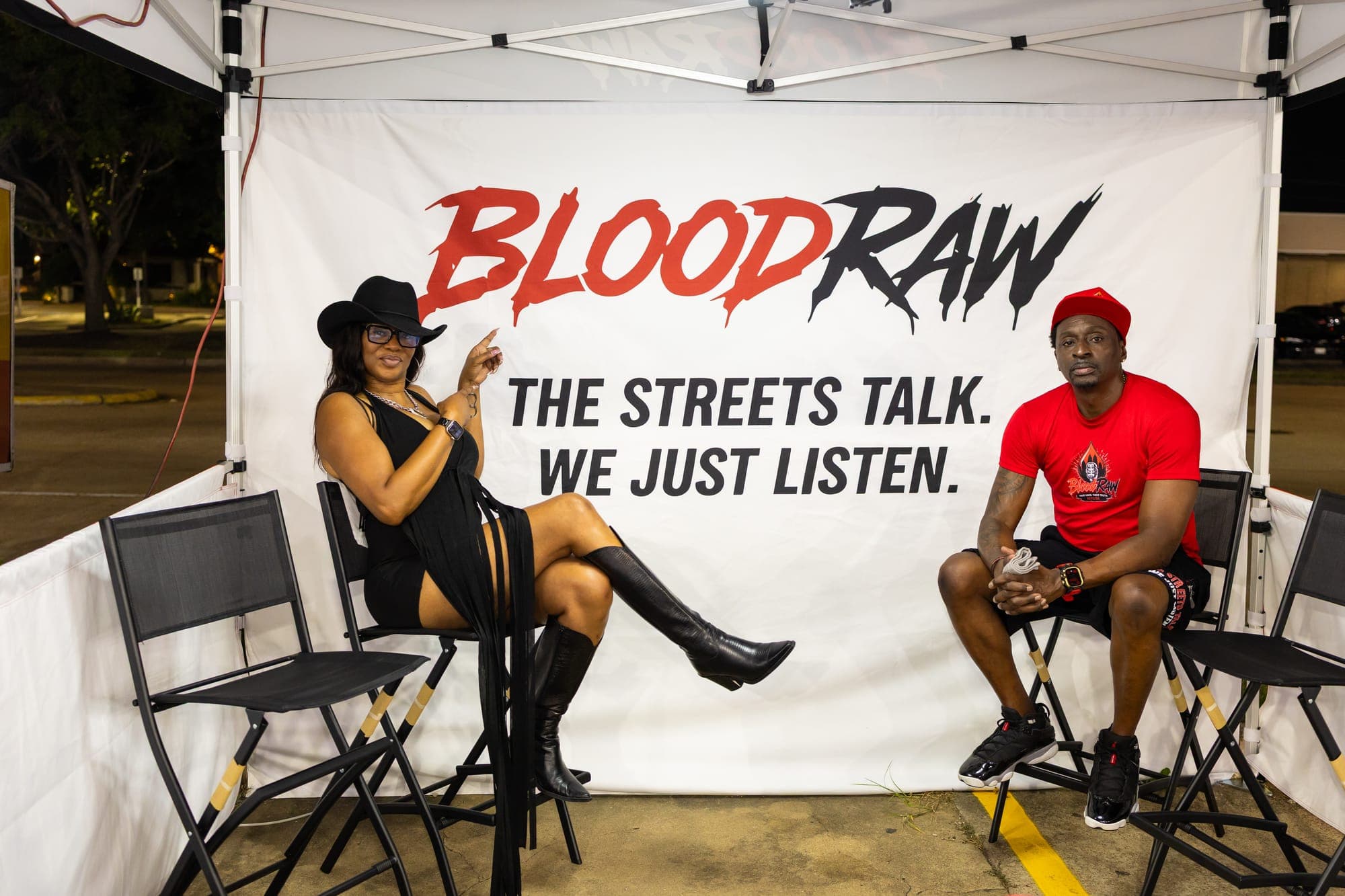 Inside the tent: two people seated in the interview chairs in front of the BloodRaw banner.